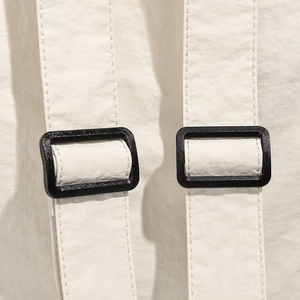 Detailed close-up of off-white backpack shoulder straps with black adjustable buckles