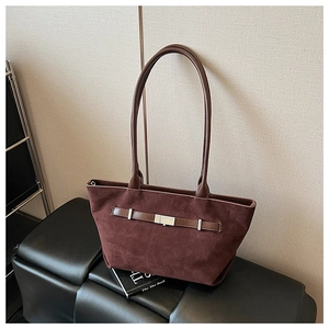 Detail of dark brown suede tote bag featuring silver buckle and leather handle on a bench
