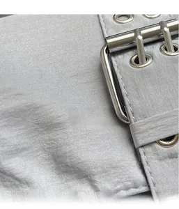 Détail macro de la bandoulière en toile gris argenté avec boucle en métal et oillets
