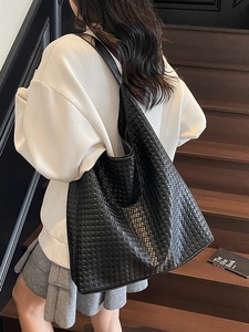 Fashionable black woven leather tote bag shown from a side perspective on a model