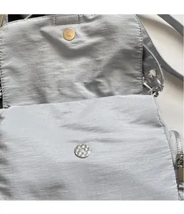 Détail du fermoir magnétique et texture sur sac à bandoulière en nylon gris clair