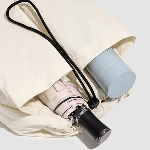 Detail view of a beige drawstring backpack storing a pink umbrella and a blue water bottle