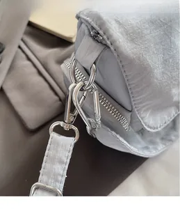 Détail du sac bandoulière argenté montrant les crochets métalliques polis et la texture
