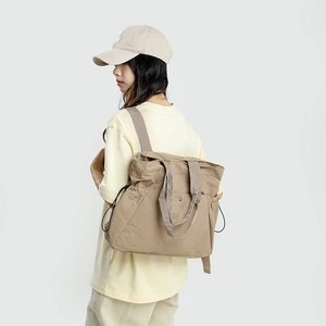 Rear view of khaki waterproof nylon backpack on model showing dual carrying options