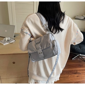 Détail du sac à bandoulière gris argenté avec texture plissée élégante et boucle décorative