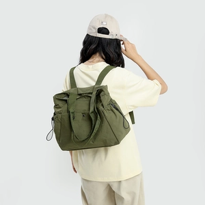 Detail of waterproof dark green nylon backpack showing side drawstring and wide straps