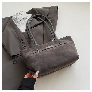 Detail of grey suede tote bag with metal buckle strap on a grey suit jacket