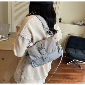 Détail du sac utilitaire en nylon gris clair avec sangles à œillets et fermeture éclair argentée