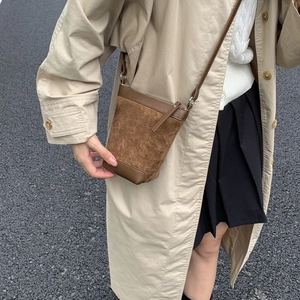 Detail of a brown matte bucket bag with zip closure and adjustable slim shoulder strap