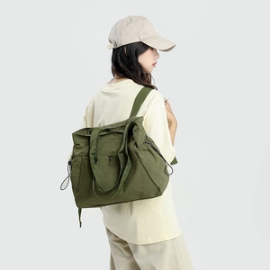 Model wearing large olive green nylon tote bag with drawstring closure for daily commute