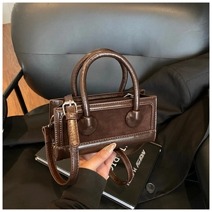 Detail of dark brown leather handbag featuring mixed textures and silver buckle strap