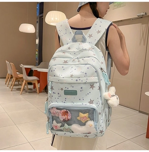 Detail view of light blue star print backpack with transparent front pocket and bear charm
