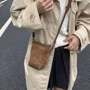 Close-up of a brown matte suede bucket bag with leather accents and shoulder strap
