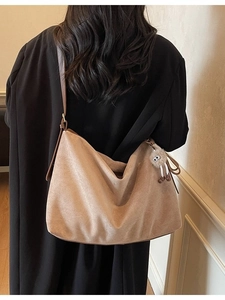 Sac fourre-tout marron en daim avec pendentif en peluche porté sur l'épaule