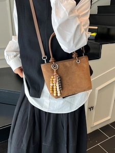 Brown faux suede tote bag with decorative wooden beads and adjustable cross-body strap