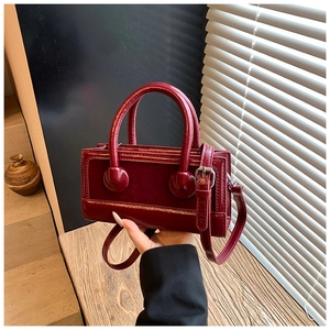 Detail of red box-shaped tote bag in patent and suede leather with metallic buckle