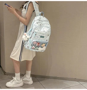 Detail of light blue backpack with star prints, transparent pocket and plush bunny charm