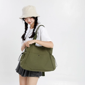 Detail view of olive green canvas tote with adjustable side drawstrings and front pocket