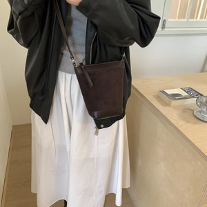 Brown vintage frosted bucket bag styled in a cozy home setting with a leather shoulder strap