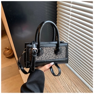 Detail of black faux leather handbag with leopard print panel and round top handle