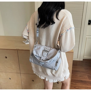 Détail du sac bandoulière en toile grise avec boucle argentée et fermetures éclair