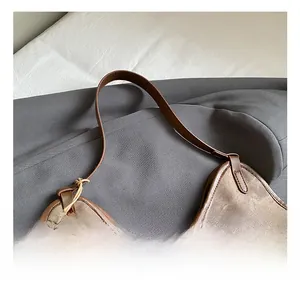 Detail of vintage brown bucket bag showing smooth curved edge and stitching on shoulder strap