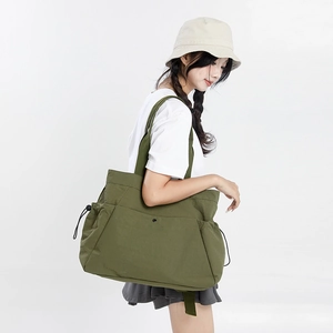 Army green nylon tote bag with drawstring side detail shown on model in studio