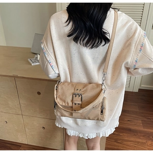 Détail du sac bandoulière en toile avec boucle métallique et fine sangle d'épaule