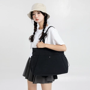 Side view of large black waterproof nylon tote bag with drawstring detail and metal buckle