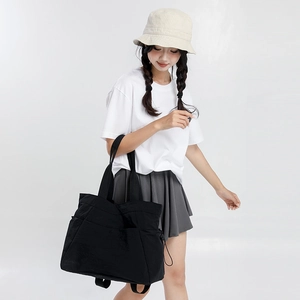 Action shot of a large black waterproof tote bag being carried on a model's shoulder