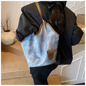 Detail of light blue marble tote with brown leather trim and shoulder strap on a model