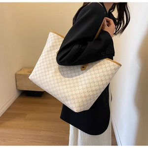 Detailed macro view of monogrammed tote bag with cream leather and brown M-pattern