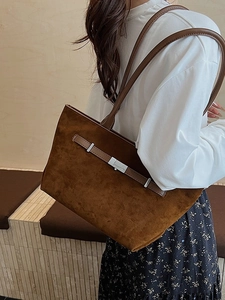 Chic caramel brown suede tote bag with silver square buckle worn by a model