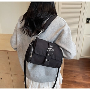 Vue détaillée du sac bandoulière en nylon noir avec boucles argentées et poches zippées