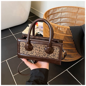 Close-up of vintage brown crossbody bag featuring stylish leopard print panel and hand grip