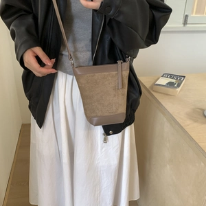 Detailed view of vintage brown suede crossbody bucket bag on a natural wooden table