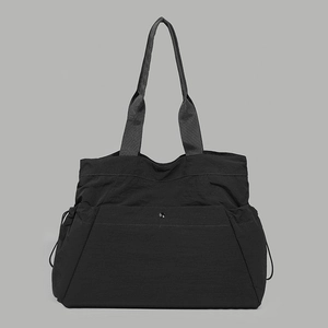 Detail view of large black waterproof nylon tote bag with drawstring and snap pocket