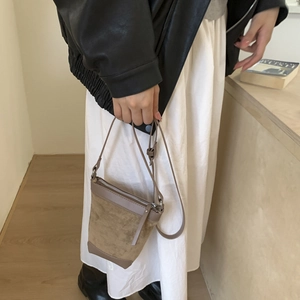 Detail of vintage matte bucket bag in tan suede with silver zipper and slim strap