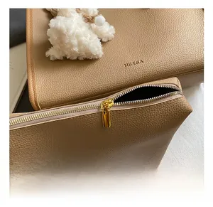Detail of light brown lychee grain leather tote with gold zipper and bunny charm