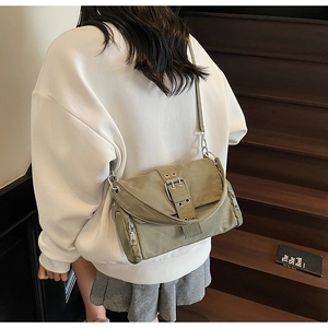 Détail du sac bandoulière vert olive en toile avec boucles argentées sur l'escalier