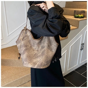 Detailed side view of large brown marble pattern hobo bag worn by a model