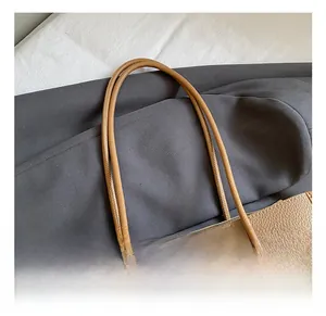Detail of the round leather handle and knit hat charm on a beige textured tote bag