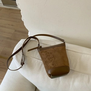 Detail of vintage brown suede bucket bag featuring smooth leather trim and silver hardware
