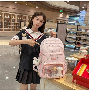 Pink star-patterned school backpack featuring a transparent window pocket and cute plush charm