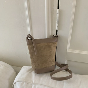Detail view of khaki suede bucket bag with adjustable shoulder strap and leather trim