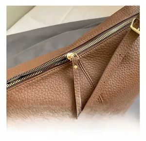 Close-up of golden metal zipper detail on brown lychee pattern leather tote bag
