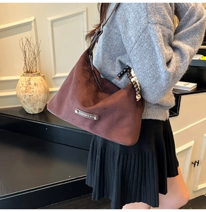 Close-up of vintage dark brown suede hobo bag with bead strap and silver metal logo tag