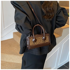 Detail of a chic leopard print handbag with glossy brown finish and rounded handles