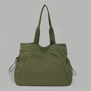 Close-up of army green nylon tote bag with side drawstrings and metal snap closure detail