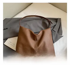 Detail of brown litchi pattern hobo bag with adjustable metallic strap and vertical stitching